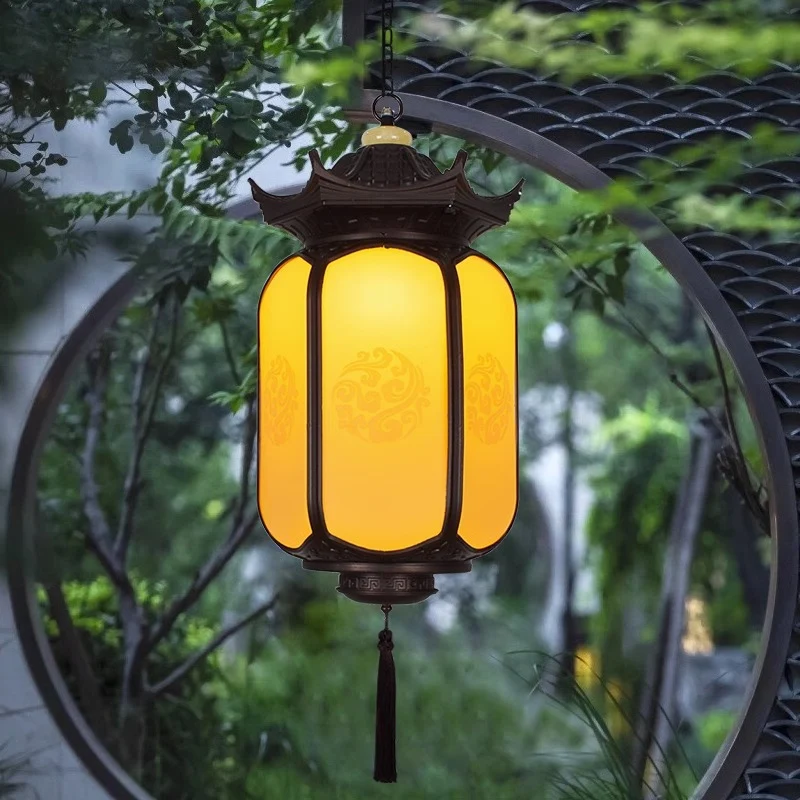 Đèn thả lồng đèn SLDTLTC sáng vàng ấm treo trước cổng tròn giữa sân vườn cây xanh