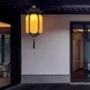 Đèn thả lồng đèn SLDTLTC sáng vàng ấm treo hiên nhà tường trắng, sàn gỗ lúc trời tối