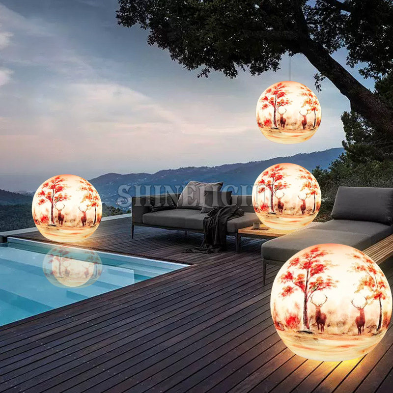 Đèn LED hình quả bóng sơn PE đặt sàn gỗ và treo cạnh hồ bơi, sofa ngoài trời lúc chạng vạng