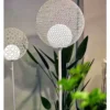 Hai đèn quả cầu hoa sắt rỗng sáng trắng đặt cạnh cây xanh sát tường