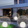 Ba đèn quả cầu hoa sắt rỗng đặt sàn trên bãi cỏ trước biệt thự hiện đại