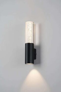 Đèn LED tường 673 hình trụ thân đen, ống thủy tinh bọt khí, hắt sáng vàng xuống tường xám
